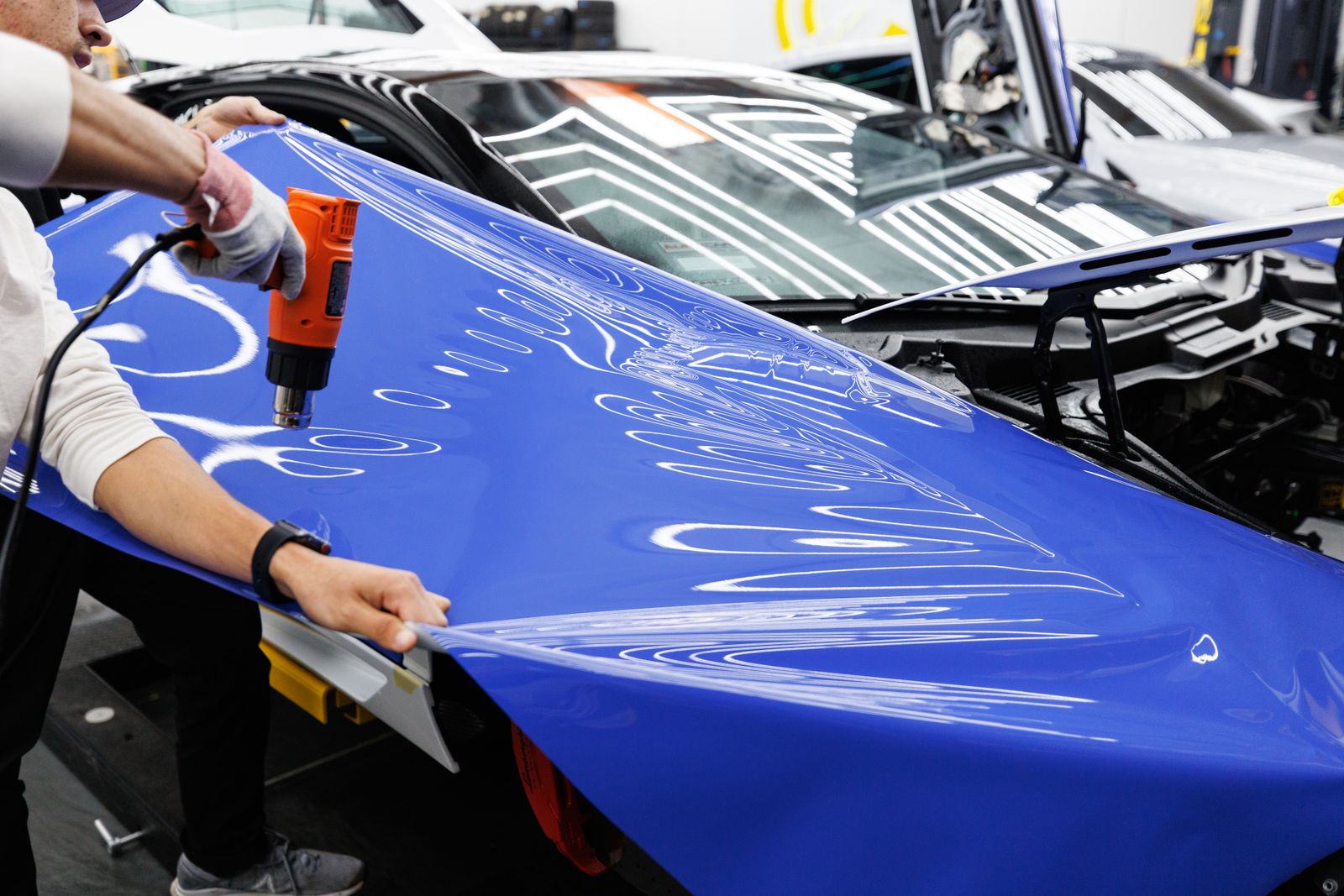 Installer heating blue colour film onto a car hood